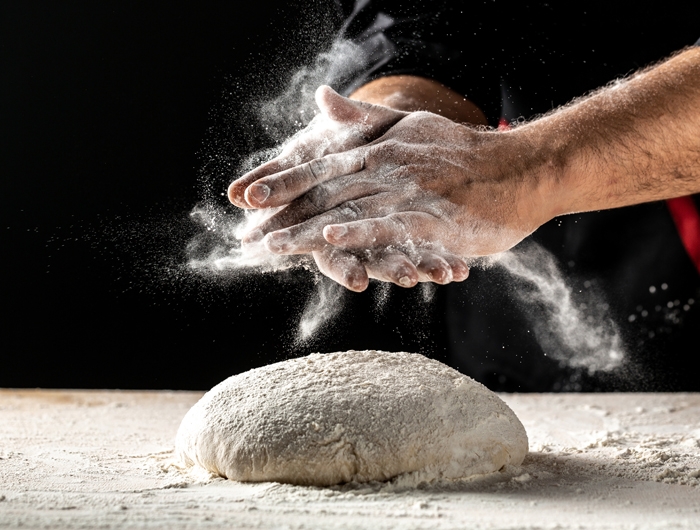 2 hands and raw dough covered in flour for baking